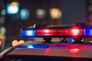 Red and blue police lights flashing on top of a patrol car at night.