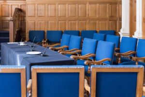 Empty jury box with blue chairs and wooden paneling in a formal courtroom setting, representing the jury selection process.