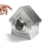 Hand reaching toward a metal safe with a circular combination dial.